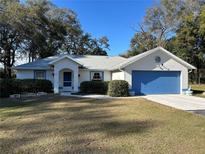 Single-story house with blue garage door and well-maintained lawn at 3899 Se 80Th St, Ocala, FL 34480