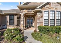 Charming stone home featuring a covered entrance, double doors, and lush landscaping at 4020 Se 9Th Ave, Ocala, FL 34480