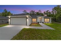 Beautiful single-story home featuring a two-car garage, manicured lawn, and a welcoming entryway at twilight at 55 Locust Loop Cir, Ocala, FL 34472