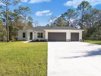 Single-story home with three-car garage and landscaped lawn at 7323 Sw 204Th Ave, Dunnellon, FL 34431