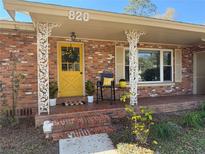 Charming brick home featuring a cozy front porch with decorative columns and a bright yellow front door at 820 Ne 42Nd Ter, Ocala, FL 34470