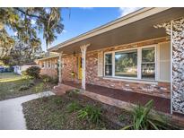 Brick ranch house with a covered porch and mature landscaping at 820 Ne 42Nd Ter, Ocala, FL 34470