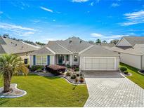 Single-story home with landscaped yard, paver driveway, and two-car garage at 1918 Walden Way, The Villages, FL 32162