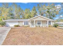 Tan house with white trim, a covered porch, and a spacious yard at 8137 Sw 117Th Loop, Ocala, FL 34481