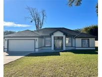 A newly constructed home with a white exterior, dark accents, and a well-manicured lawn at 1846 Ne 127Th Pl, Anthony, FL 32617