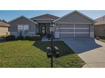 Single-story home with gray exterior, two-car garage, and well-manicured lawn at 8652 Se 133Rd Ln, Summerfield, FL 34491