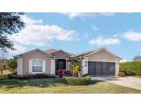 Tan one-story house with a three-car garage and manicured landscaping at 15692 Sw 11Th Court Rd, Ocala, FL 34473