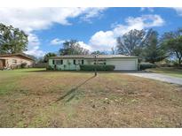 Ranch-style home with a green exterior, a spacious yard, and a two-car garage at 2004 Ne 52Nd St, Ocala, FL 34479