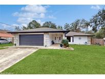 Single-story home with stone accents, a two-car garage, and a well-maintained lawn at 21668 Sw Peach Blossom St, Dunnellon, FL 34431