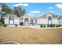 Charming single-story home with white exterior, blue trim, landscaped yard, and arched windows at 7528 Sw 102Nd Loop, Ocala, FL 34476