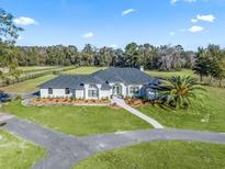 Aerial view of a home with expansive green pastures and equestrian facilities at 7675 W Highway 326, Ocala, FL 34482