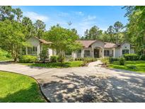 Stately stucco home with a circular driveway, mature trees, and professionally landscaped front yard at 995 Sw 37Th Place Rd, Ocala, FL 34471