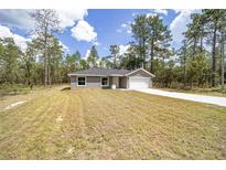 Newly constructed house with a driveway and surrounded by lush trees at 117 Nw Sparrow Rd, Dunnellon, FL 34431