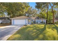 Cute light blue house with a white garage door and green lawn at 2340 Ne 43Rd St, Ocala, FL 34479