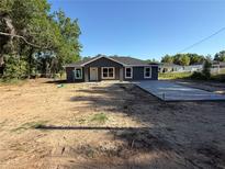 Charming single-story home featuring a gray exterior, white trim, and newly installed concrete driveway at 5411 Nw 7Th Pl, Ocala, FL 34482
