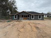 New construction home with gray siding, a black roof, and white trim ready for landscaping at 5411 Nw 7Th Pl, Ocala, FL 34482