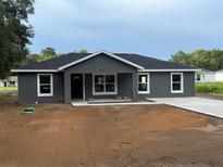 Charming single-story home featuring a modern gray exterior, black roof, and a well-manicured front yard ready for landscaping at 5411 Nw 7Th Pl, Ocala, FL 34482