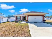 One-story home with attached garage, stone accents, and landscaping at 7646 Sw 129Th Pl, Ocala, FL 34473