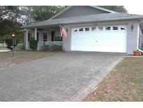 Brick ranch home with a large white garage door and paver driveway at 9662 Sw 97Th Ln, Ocala, FL 34481