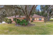 Single-story house with a tree-covered yard and a paved driveway at 10090 Sw 78Th Ct, Ocala, FL 34476