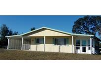 Single-story house with light yellow walls, green roof, and covered porch at 10470 Sw 99Th Ave, Ocala, FL 34481