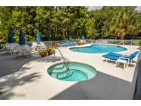 Community pool and spa with lounge chairs and patio tables at 20820 River Dr # B17, Dunnellon, FL 34431