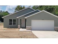 Charming single-story home featuring a gray exterior, a two-car garage, and decorative stone accents on the facade at 24300 Sw Sea Cliff Ave, Dunnellon, FL 34431