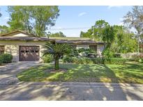 Tan house with brown garage door and nicely landscaped yard at 3856 Ne 19Th Street Cir, Ocala, FL 34470