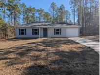 Newly constructed home with a grassy yard and driveway at 963 Sw Temple Heights Ct, Dunnellon, FL 34431