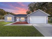 Gray house with white garage door, landscaping, and walkway at 66 Teak Loop, Ocala, FL 34472