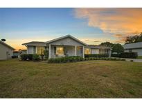 Charming single-story home with a well-manicured front yard and covered porch at sunset at 8188 Sw 108Th Loop, Ocala, FL 34481