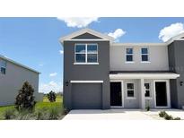 Stylish two-story home with a grey stucco facade, a garage, and a well-maintained front lawn at 8406 Gower Trl, Wildwood, FL 34785