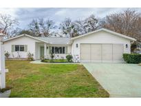 White single-story house with a two-car garage and well-maintained lawn at 10882 Sw 62Nd Ave, Ocala, FL 34476