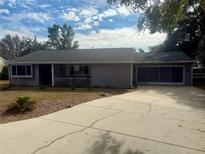 Charming single story home with a gray exterior, driveway, and partial view of the yard at 10895 Sw 90Th Ter, Ocala, FL 34481