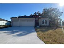 Charming single-Gathering home featuring a two-car garage, neutral color palette, and neatly maintained front lawn at 19448 Sw 78Th Pl, Dunnellon, FL 34432