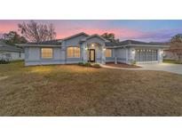 House exterior featuring gray siding, landscaping, and a screened garage at 10628 Sw 74Th Ave, Ocala, FL 34476