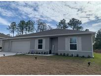 Gray house with a two-car garage, landscaping, and a small front yard at 15155 Sw 52 Cir, Ocala, FL 34473