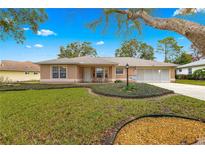 Tan one-story house with mature landscaping and a large yard at 6151 Sw 84Th St, Ocala, FL 34476