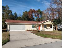 Cute yellow house with red door, screened garage, and landscaped yard at 8623 Sw 108Th Place Rd, Ocala, FL 34481