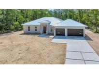 Stunning new construction home with metal roof, modern wood front door and concrete driveway at 6877 Sw 131St Cir, Ocala, FL 34481