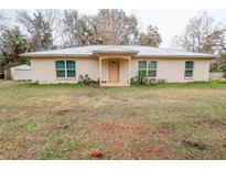 Beige house with metal roof, light brown door, and green lawn at 70 Se 81St Pl, Ocala, FL 34480