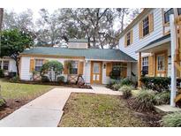 Front view of charming house with green roof and yellow accents at 7990 Midway Drive Ter # M102, Ocala, FL 34472