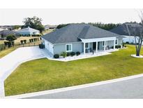 Gray house with a three-car garage and rocking chairs on the porch at 9645 Se 61St Ter, Belleview, FL 34420