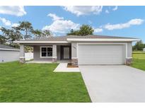 Newly constructed one-story home with gray exterior, stone accents, and a two-car garage at 10120 Se 130Th St, Belleview, FL 34420