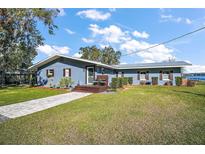 Newly renovated waterfront home with a gray exterior, landscaping, and a spacious yard at 10455 Se 143Rd St, Summerfield, FL 34491