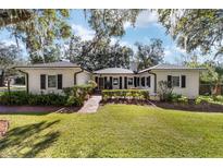 White brick home with black shutters, landscaping, and a spacious lawn at 1758 Se 7Th St, Ocala, FL 34471