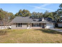 Newly renovated home with gray siding, fresh landscaping, and a white garage door at 43 Teak Crse, Ocala, FL 34472