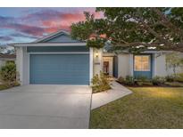 Charming single-story home featuring a blue garage door, lush landscaping, and a warm, inviting entrance at 1065 Ne 31St Ter, Ocala, FL 34470