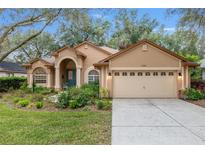 Tan house with teal door, arched entryway, and landscaped yard at 19586 Sw 84Th Pl, Dunnellon, FL 34432