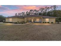 One-story house with screened porch, landscaped yard, and sunset view at 21590 Sw 84Th Loop, Dunnellon, FL 34431